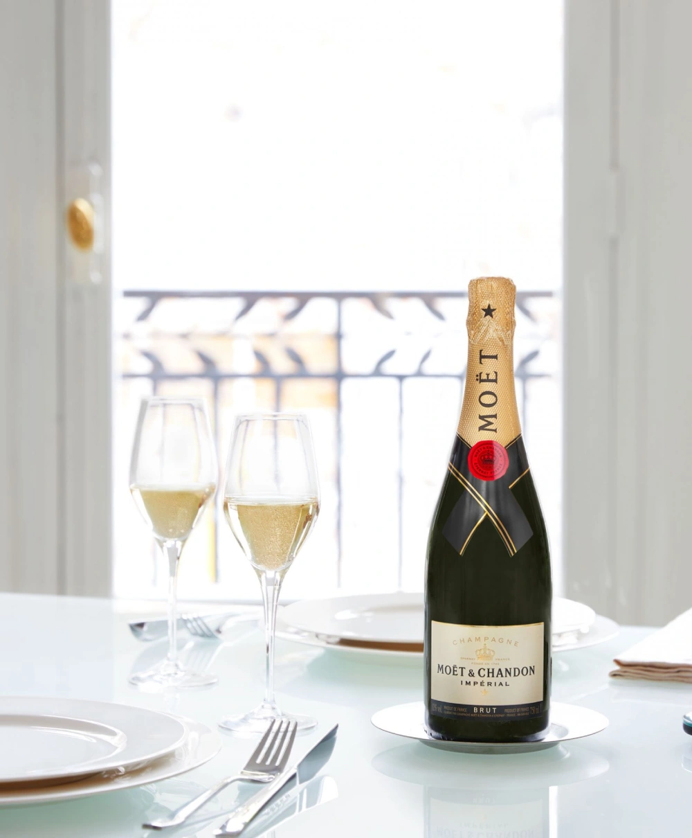 Moët & Chandon Brut Impérial champagnefles met twee gevulde champagneglazen op tafel